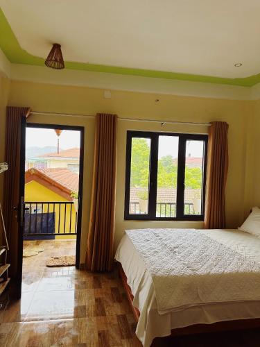 a bedroom with a bed and two large windows at Phong Nha Ecolodge Homestay By HOFs in Phong Nha