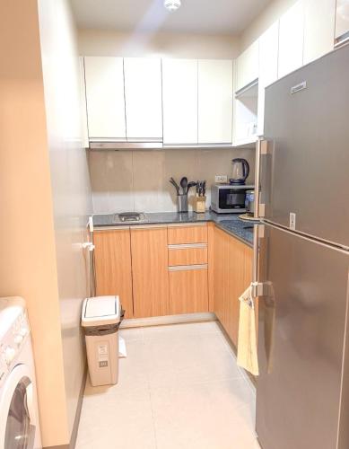 a small kitchen with a refrigerator and a microwave at The Mactan Newtown Beach Condo in Lapu Lapu City