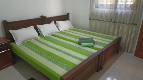 a bedroom with a bed with a green and white bedspread at Family Holiday Inn in Badulla