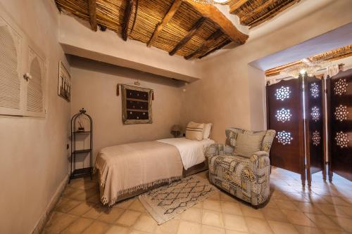a bedroom with a bed and a chair at Ksar Ighnda in Aït Ben Haddou