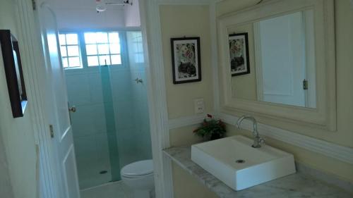 a bathroom with a sink and a shower and a mirror at Casas de férias in Guarujá