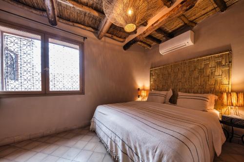 a bedroom with a large bed and two windows at Ksar Ighnda in Aït Ben Haddou