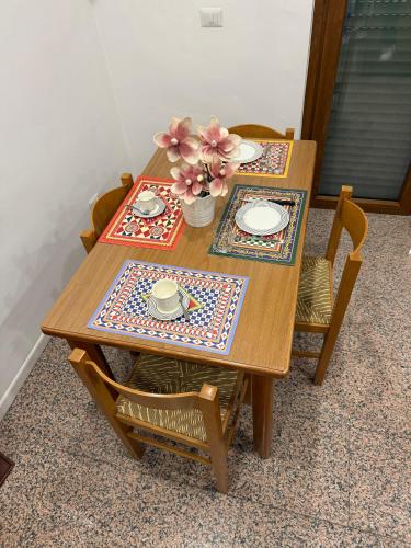 a wooden table with two chairs and a table with flowers on it at Rest Guesthouse 2,0 in Melito di Porto Salvo