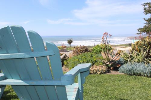 a blue chair sitting on the grass near the beach at Cambria Shores Inn in Cambria