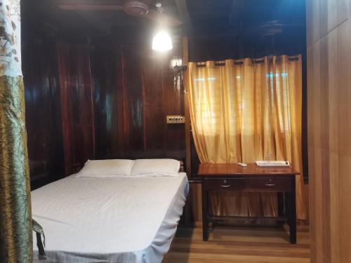 a small bedroom with a bed and a dresser with a window at Kailasahomestay & Ayurvedic Spa in Pūvār