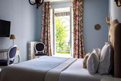 a bedroom with a bed and a window with chairs at Hôtel du Mail in Angers