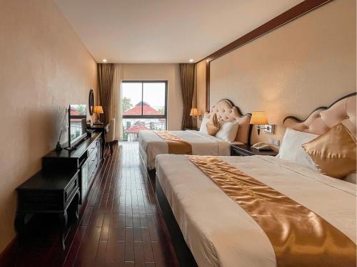 a hotel room with two beds and a television at Mira Boutique Hotel Quy Nhon in Quy Nhon