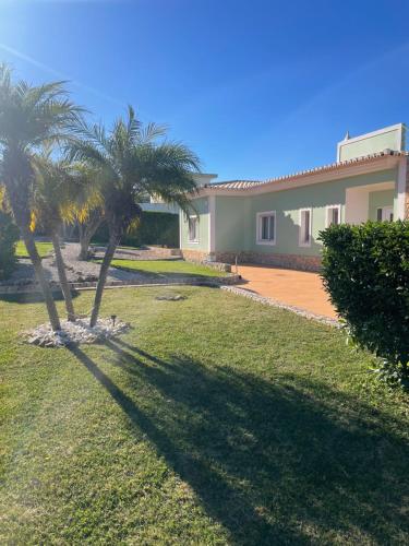 a house with two palm trees in the yard at Casa Luar- suite rooms in Praia do Carvoeiro