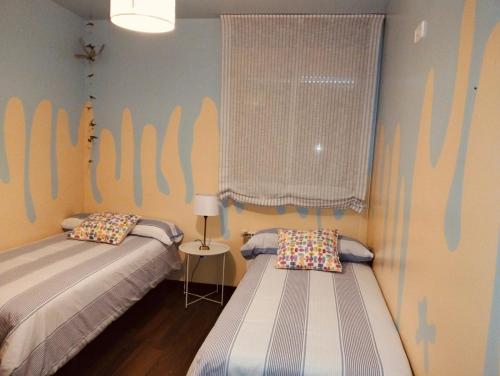 Un dormitorio con dos camas y una ventana. en El Hogar de Pepe, en El Casar de Escalona