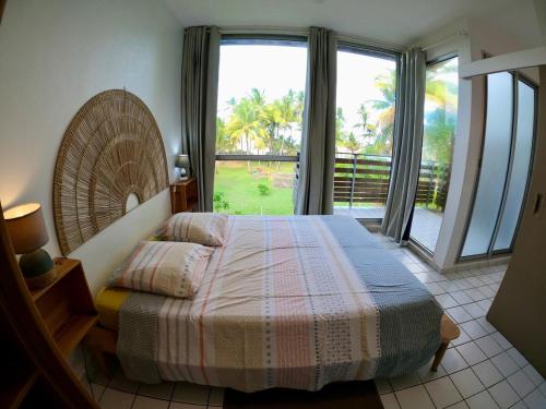 a bedroom with a bed and a large window at Appartement F3 accès plage Montjoly Roches Compas in Montjoly