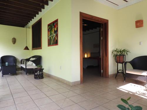 a living room with chairs and a door to a room at Playa Negra Guesthouse in Cahuita