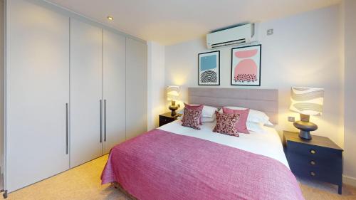 a bedroom with a large bed with pink sheets and pillows at Cheval Harrington Court at South Kensington in London