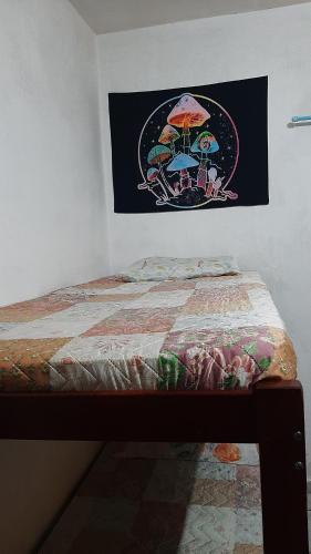 a bed with a picture of umbrellas on the wall at Renovo Beija-flor Hostel e Espaço Terapêutico in Bertioga