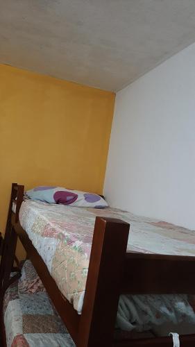 a small bed in a room with a yellow wall at Renovo Beija-flor Hostel e Espaço Terapêutico in Bertioga