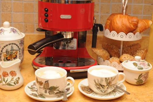 a red coffee maker on a counter with cups and pastries at A&B Le Terrazze del Sale' - Apartments in Trento