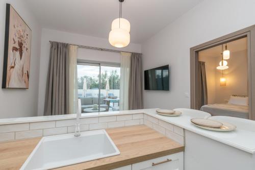 a white kitchen with a sink and a mirror at Camelia Luxury Suites in Psarou