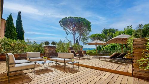 a wooden deck with chairs and tables and umbrellas at Le Pigonnet - Esprit de France in Aix-en-Provence