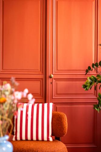 a red door with a red and white striped pillow on a chair at Hôtel du Mail in Angers