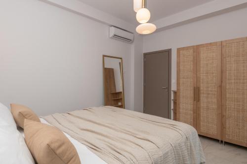 a white bedroom with a bed and a mirror at Camelia Luxury Suites in Psarou
