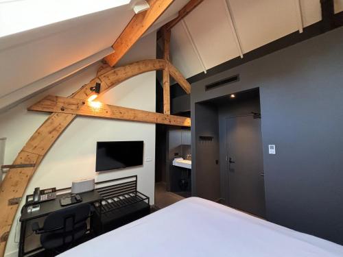 a room with a bed and a tv on a wall at Kazerne Hotel - Member of Design Hotels in Eindhoven