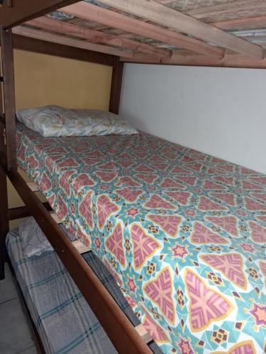 a bunk bed with a colorful quilt on it at Renovo Beija-flor Hostel e Espaço Terapêutico in Bertioga