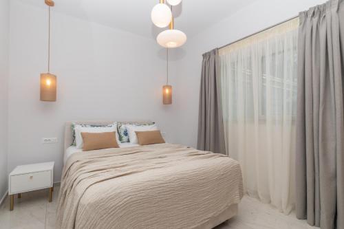 a white bedroom with a bed and a window at Camelia Luxury Suites in Psarou