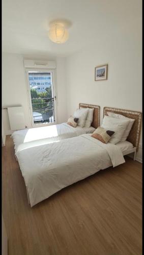 - une grande chambre blanche avec 2 lits et une fenêtre dans l'établissement Le Central - Bel appartement lumineux proche Paris, à Saint-Ouen