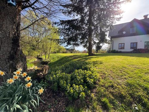a house with a tree and flowers in a yard at Penzion Terezka in Králíky