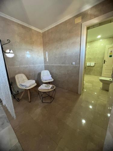 a bathroom with two chairs and a toilet in it at Hotel Restaurante Dama de Baza in Baza