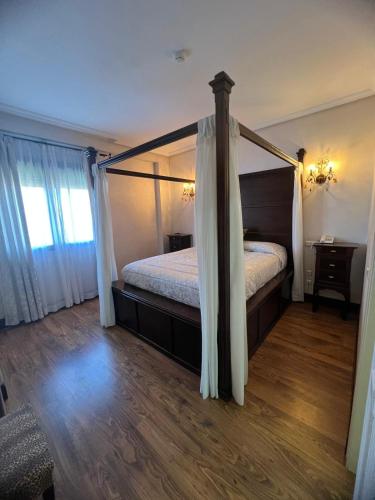 a bedroom with a canopy bed and a wooden floor at Hotel Restaurante Dama de Baza in Baza