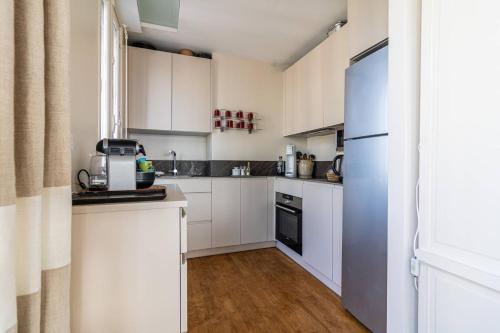 Elle comprend une petite cuisine avec des placards blancs et un réfrigérateur. dans l'établissement Saint-Jean de Luz, appartement 5 couchages avec vue océan - parking, à Sainte-Barbe