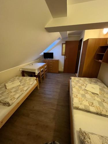 a room with two beds and a table and chairs at Penzion Pod Zámkem in Pruhonice
