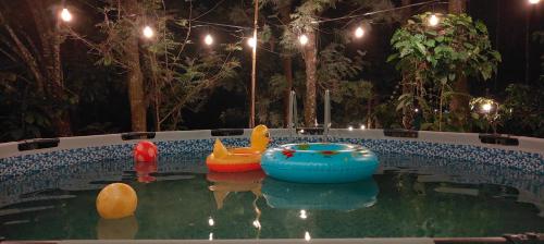a pool with two inflatable boats in the water at night at Cicadas Nature Resort - A Frame cottages in Wayanad