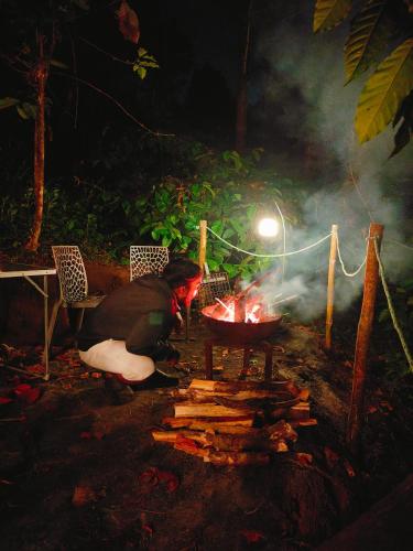 a person is cooking over a fire at night at Cicadas Nature Resort - A Frame cottages in Wayanad