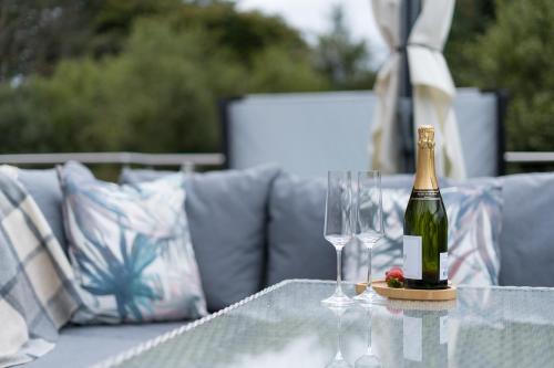 a bottle of champagne and two wine glasses on a table at The Heronry Hideaway with luxury hot tub in Ballachulish