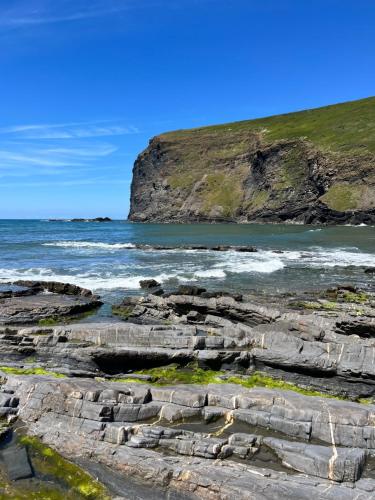 a view of the ocean and rocks on the beach at Ivy Rose Cabin No Hot Tub in Bude