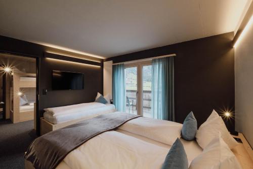 a hotel room with two beds and a window at Frutigresort in Frutigen
