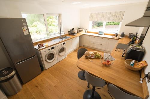 a kitchen with a table and a refrigerator at The Heronry Hideaway with luxury hot tub in Ballachulish