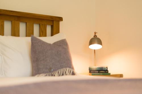 a bed with a pillow and a lamp on a table at The Heronry Hideaway with luxury hot tub in Ballachulish