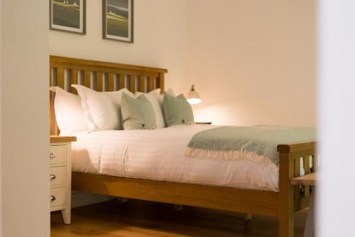 a bedroom with a wooden bed with white pillows at The Heronry Hideaway with luxury hot tub in Ballachulish