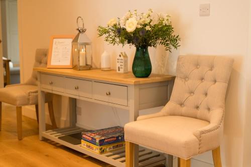 a desk with a vase of flowers and two chairs at The Heronry Hideaway with luxury hot tub in Ballachulish