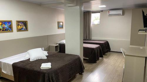 a hotel room with two beds and a window at Hotel Zata - Premium in Criciúma