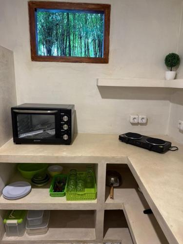 a kitchen with a microwave on a kitchen counter at Villa Anjing in Nusa Dua