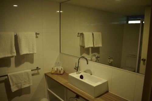 
a bathroom with a sink, mirror, towel rack and towel dispenser at Motel 98 in Rockhampton
