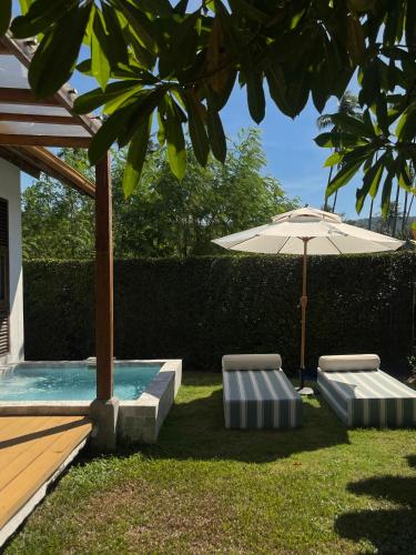 two chairs and an umbrella next to a pool at Rest Sea Resort Koh Kood in Ko Kood