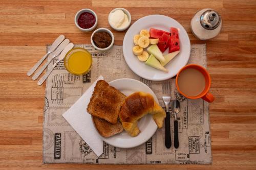 two plates of food with toast and fruit on a table at Planta Alta Bed & Breakfast in Buenos Aires
