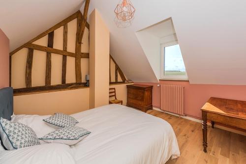 - une chambre avec un lit blanc et une table en bois dans l'établissement Grand Gîte des Hautes Maisons, à Guainville