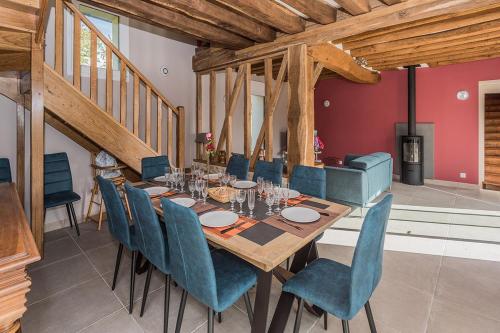 une salle à manger avec une table en bois et des chaises bleues dans l'établissement Grand Gîte des Hautes Maisons, à Guainville