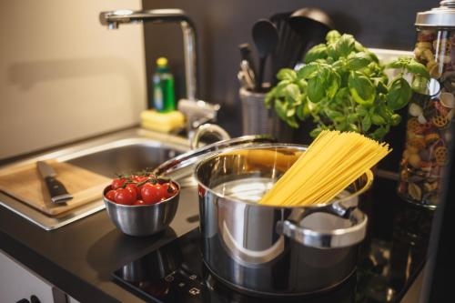 a pot on a stove with pasta and tomatoes at The Circus Living in Berlin