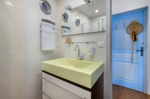 La salle de bains est pourvue d'un lavabo et d'une porte bleue. dans l'établissement Sur le Port du Croisic - Appartement pour 4, au Croisic